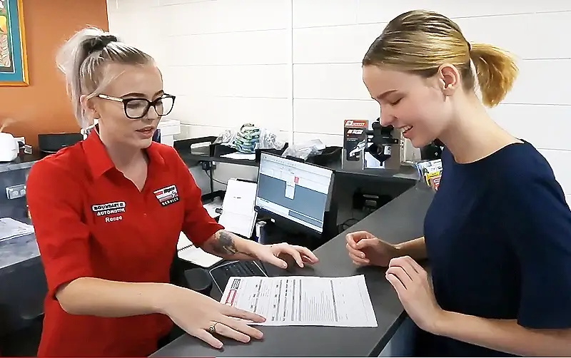 Townsville mechanic shows repair quote to female customer in railway estate office