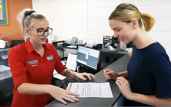 Townsville mechanic shows repair quote to female customer in railway estate office